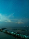 Sea view near mangrove forest with man made wooden barrier for wave protection, under starry nigh cloudy sky Royalty Free Stock Photo