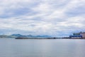 The sea view and port with sky is full of clouds. There is mountain on background