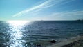 Sea view from the shore on a sunny day. Calm sea with light ripples on the surface of the water, sun glare, blue sky with light cl Royalty Free Stock Photo