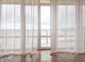 Sea view through a transparent curtain on a huge panoramic window with a balcony, modern interior of apartments in a Royalty Free Stock Photo