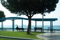 Sea view and unrecognizable man sitting on the beach near a pier and looking on the sea Royalty Free Stock Photo