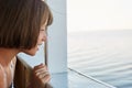 Sea voyage concept. Little girl with bobbed hair having sea trip on ship, looking from deck, watching sea with excited look. Cute