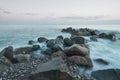The sea washes the big rocks against the pink sunset. Photo on a long exposure. Royalty Free Stock Photo