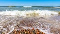 Sea water with little waves and many stones shore