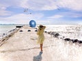 Sea water splash on pier women in yellow dress with blue air ball walk on horizon bright white cloudy sky seagull fly panorama lif