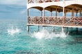 Sea water splashes after jumping to the ocean on light green ripples background in tropical warm destination next to wooden