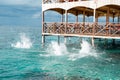 Sea water splashes after jumping to the ocean on light green ripples background in tropical warm destination next to wooden