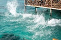 Sea water splashes after jumping to the ocean on light green ripples background in tropical warm destination next to wooden