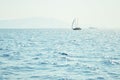 Sea water surface and waves stretch out to the horizon where islands are visible far away.