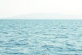 Sea water surface and waves stretch out to the horizon where islands are visible far away.