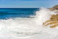 Sea water waves with white foam splash on rocks at shore Royalty Free Stock Photo