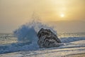 Sea wave beating with force against the rock at sunset