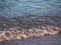 Sea wave close-up, low viewing angle. Water near the shore. Light foamy waves of the sea near the sandy shore. Texture of seawater Royalty Free Stock Photo