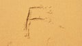 The sea wave erases the inscriptions written on the sand. top view. the letter f