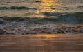 Sea wave foam on sandy beach in sundown light, close up. Tropical summery background Royalty Free Stock Photo