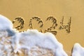 Sea wave with foam washes away the inscription 2024 Royalty Free Stock Photo