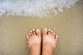 Sea wave with male foot on the sand Royalty Free Stock Photo