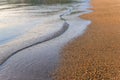 Sea wave and sand seashore. Golden sun light over the sea ocean waves. MIrror reflection on water surface. Macro close up Royalty Free Stock Photo