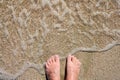 The sea wave on a sandy beach washes men`s feet. Royalty Free Stock Photo