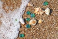 Sea wave, shells and glass pebbles on the wet sand