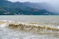 Sea wave in stormy weather. The turbid wave. Low clouds over the coast. Montenegrin beach in rainy weather. The sea and mountains Royalty Free Stock Photo