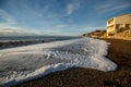 Sea wave surf and foam on sandy empty foam beach and nice blue sky. Wide angle view Royalty Free Stock Photo