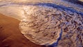 Sea wave with white foam rolls over sandy shore of beach. Top view. Royalty Free Stock Photo