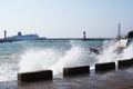 Sea waves breaking on the pier, resort embankment, sun glare on the water.