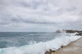 Sea waves breaking on a stone wall on the shore with buildings in the background on the Malecon in Cuba Royalty Free Stock Photo