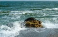 Sea waves crashing against rocks on a sand and stone beach Royalty Free Stock Photo