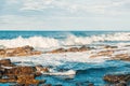 Sea waves crashing on rocks in sunny day against cloudy sky Royalty Free Stock Photo