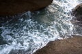 Sea waves foam between cliff stones