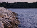 Sea waves hit the stones on the seashore. On the horizon is a forest Royalty Free Stock Photo