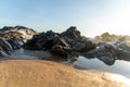 Sea waves lapping gently on the dark rocks of the beach