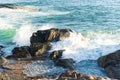 Sea waves lapping gently on the dark rocks of the beach