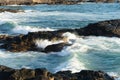 Sea waves lapping gently on the dark rocks of the beach