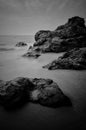 Sea waves lash line impact rock on the beach. Black and white photography.