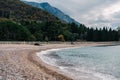 Sea waves roll on the beach at the stone fence of the green garden at the foot of the mountains Royalty Free Stock Photo