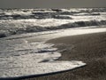 Sea waves roll over the sandy shore. The foam slides along the shore back into the sea.