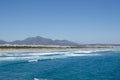 Sea, waves, sandy beach and mountains behind