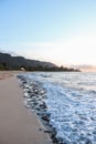 Sea waves on a sandy beach near to mountains under dusk sky in Oahu Island, Hawaii, Vertical shot Royalty Free Stock Photo