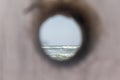 Sea with waves seen through a hole carved tree trunk; at the seaside