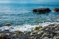 Sea waves splashes around rocks on a pebble beach. Seascape. Selective focus