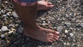 A sea waves on a stone beach covering the rocks and male feet. Media. Close up of man standing on the sea shore, summer Royalty Free Stock Photo