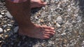 A sea waves on a stone beach covering the rocks and male feet. Media. Close up of man standing on the sea shore, summer Royalty Free Stock Photo