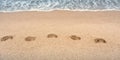 Sea waves wash away footprints on the sandy beach at the water\'s edge. Royalty Free Stock Photo