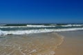 Sea waves wash the beach against a blue sky. Landscape on a wild beach. The sea in the summer Royalty Free Stock Photo