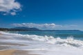 Sea waves and white foam on paradise sandy beach, blue sky, white clouds. Royalty Free Stock Photo