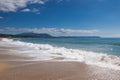 Sea waves and white foam in paradise sandy beach, blue sky, white clouds. Royalty Free Stock Photo