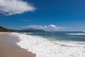 Sea waves and white foam in paradise sandy beach, blue sky, white clouds. Royalty Free Stock Photo